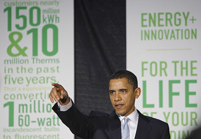 U.S. President Barack Obama speaks in front of banners that extol the virtues of alternative energy. via skip-to-the-end.com