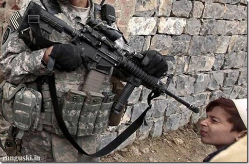 An Afghan villager looks through a gun while a U.S. Army soldier from Task Force Denali Battle team 1-40 CAV patrols at Shembawut village in Khowst province December 14, 2009.  REUTERS/Zohra Bensemra  (AFGHANISTAN - Tags: CONFLICT MILITARY IMAGES OF THE DAY)