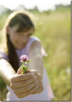 Girl holding out flower, focus on flower in foreground