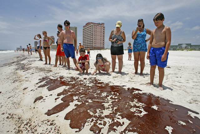 Beach goers stare at at pools of oil which washed up on the beach in Gulf Shores Friday, June 4, 2010 just west of the Alabama Gulf State Park Pier. Bill Starling / Press-Register