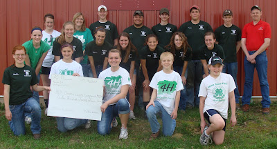 4-H members from both Benton county and 76 Progressives 4-H Club of Washington County  got to know each other better as they worked to plant five trees at the Benton County Fairgrounds in an effort to recover from last year’s storm damage.  Washington County members who helped are in white and showcasing their Pioneer Grant check that helped complete this community service project.