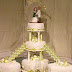 Nº140: Terminación en fondant extendido liso, con texturización simulando una carpeta de encaje. Rosas de azúcar blancas y detalles en verde manzana. Montaje sobre pilares y con escaleras para las tortas satélite.