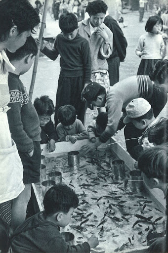 Japanese schoolchildren catching fish from a little pool. Could they be more adorable?