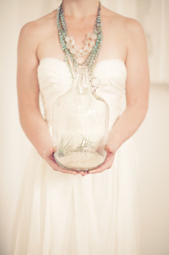 Glass jugs filled with sand and air plants decorated the space. Glass jugs filled with sand and air plants decorated the space.