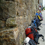 27/07. Olveiroa. La fila degli zaini "segnaposto" lungo il muro del rifugio.