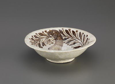 Bowl | Origin:  Samarra,  Iraq | Period: 9th century  Khalid active 9th century),  Abbasid period | Details:  This luster-painted bowl, signed by a Khalid, is a pivotal piece, linking the tradition of luster-painted ceramics, which originated and flourished in late ninth- and early tenth-century Iraq, to production in Egypt, after the gradual disintegration of the Abbasid Empire in the tenth century. The drawing of the proud bird of prey, probably an eagle or hawk, differs considerably in conception and execution from other designs found on ninth-century Abbasid luster painted ceramics, which favor highly stylized and whimsical animal forms. While still abstracted, the crisply delineated eagle is resting one talon on a desperate hare and exudes a sense of tremendous pride and presence. The eagle is further distinguished by a collar around its neck and a ribbon attached to one of its legs. The decoration of the bowl is also notable for the wreath encircling the edge of the bowl. Such motifs are found on ninth-century Abbasid tiles from Samarra, and harks back to earlier Sassanian and Byzantine motifs. | Type: Earthenware painted over glaze with luster | Size:   W: 9.1  cm | Museum Code: F2005.10 | Photograph and description taken from Freer and the Sackler (Smithsonian) Museums.