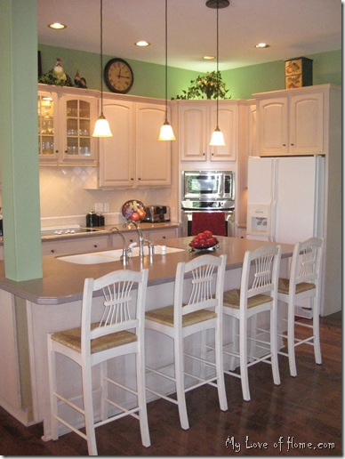 Kitchen, green walls, light cabinets, dark wood floor red accents