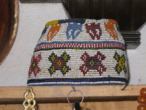 This beaded hat with its primary colors really stands out in the rough hewn space.