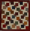 A split 9-patch quilt made by Audrey Woods and quilted in a pattern called Daisy Swirl