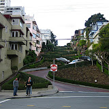 A part of Lombard Street where cars are driving downhill on a windy road