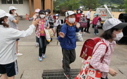 Teachers see children onto a bus after the end of lessons at Oguni Elementary School in Date, Fukushima Prefecture, on 30 June 2011. The school has instructed children to wear masks, hats and long sleeves to protect them from radioactive materials. Mainichi