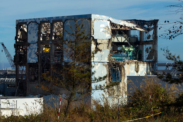 The Unit 4 reactor building of the crippled Fukushima Dai-ichi nuclear power station is seen through a bus window in Okuma, Japan Saturday, 12 November 2011. Media allowed into Japan's tsunami-damaged nuclear power plant for the first time Saturday saw a striking scene of devastation: twisted and overturned vehicles, crumbling reactor buildings and piles of rubble virtually untouched since the wave struck more than eight months ago. David Guttenfelder / Pool