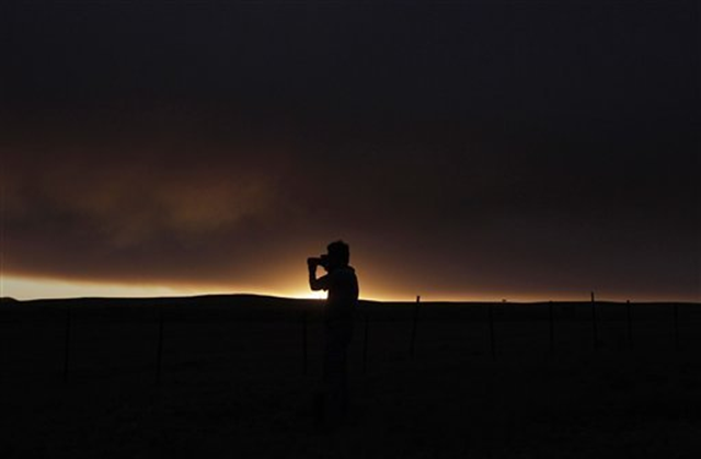 Freelance photographer Thomas Gaulke, of Germany, photographs smoke from the Wallow Fire near Springerville, Ariz., Friday, June 10, 2011. The major wildfire in Arizona's eastern mountains burned out of control early Friday after charring more than 603 square miles of timber, destroying dozens of structures and keeping thousands of evacuees away from their homes. Jae C. Hong / AP Photo