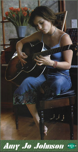 Amy Jo Johnson barefoot playing guitar singer and songwriter
