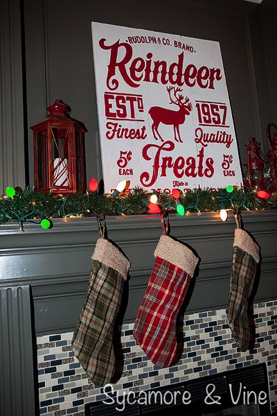 Plaid stockings on mantel with large bulbs and Reindeer Treats Sign. A truly stunning Christmas Home Tour as part of the Christmas in the Country Blog Tour. This Plaid Inspired Country Christmas will knock your socks off. Features tours of the Living room, Dining Room and a Cocoa hot chocolate bar in the Breakfast room. There is so much inspiration for Christmas decorations in this one post. Be prepared to feel like you are cuddled up by the fire in a warm Northwoods comfy cottage! #country #Christmas #Plaid #Holiday decorating #Holiday ideas #Holidays #Christmas decor #Holiday decor Plaid stockings on mantel with large bulbs and Reindeer Treats Sign.A truly stunning Christmas Home Tour as part of the Christmas in the Country Blog Tour. This Plaid Inspired Country Christmas will knock your socks off. Features tours of the Living room, Dining Room and a Cocoa hot chocolate bar in the Breakfast room. There is so much inspiration for Christmas decorations in this one post. Be prepared to feel like you are cuddled up by the fire in a warm Northwoods comfy cottage! #country #Christmas #Plaid #Holiday decorating #Holiday ideas #Holidays #Christmas decor #Holiday decor