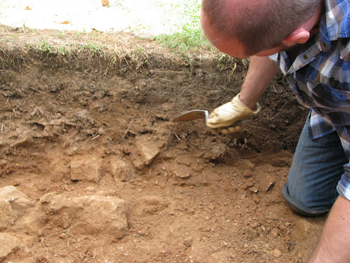 Dr. Monty Dobson pointing out the difference between the natural soil color (the darker top layer) and the constructed trench wall.
(Photo credit: Jeremy Shreckhise)