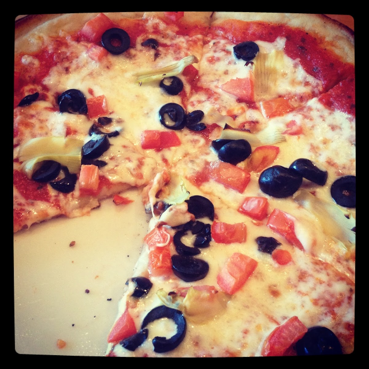 GF pizza with tomatoes, black olives and artichoke hearts