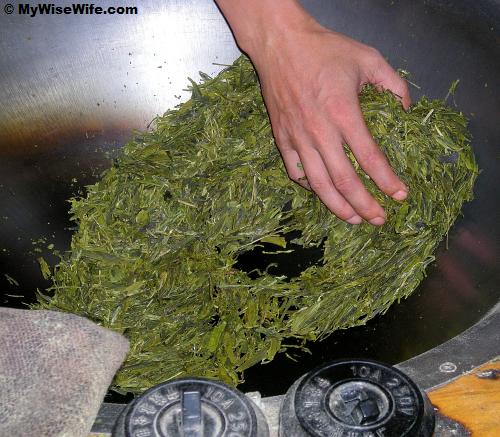 A sifu is pan-roasting Longjing tea leaves