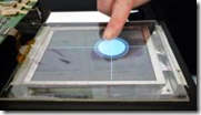 The prototyped "3D touch panel." A white circle is displayed on the area approached by a finger. The circle becomes larger as the finger moves closer to the panel.