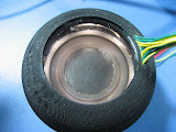 The first prototype of the Nuventix sales demo platform is lit up with the strobing LED ring-light, to show off the moving diaphragm.  The diaphragm moves at approx 70 Hz, and the strobing light pulses at about 1/4 that frequency, to slow it down for human visualization.  Though it can't be seen in this still picture, the diaphragm appears to move slowly, under the influence of the strobing LEDs.  Meanwhile, the forced air can be felt out the perimeter of the module.