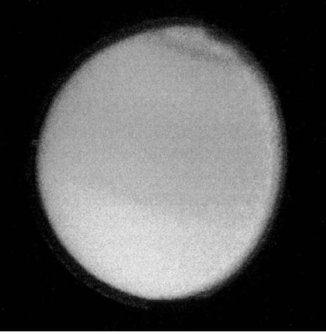 Voyager 2 image of Titan showing the thick, reddish cloud layer that obscures any surface features. A faint dark band is visible near the North Pole and the Southern Hemisphere is slightly ligher (NASA picture). This figure is available in full color at http:// www mrw. interscience.wiley. com/esst.