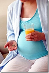 Pregnant woman holding vitamin pills and orange juice