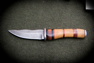 Couteau de chasse, lame en acier damas forgée à partir d'un câble de grue. Garde en acier inoxydable, manche multi-bois (ébène, buis, palissandre et cuir).