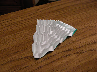 Expanded diagonal v-shaped origami accordion bottom