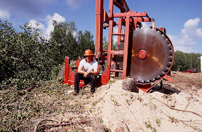 The Dirty Hands People - If you've spent as much time in the woods as we have, it's easy to convince yourself you've seen just about every logger-inspired innovation there is, but this Minnesota logger surprised us with a rubber-tired circle saw he'd built for sawing pulpwood logs to the right length for his truck. It may not look like much, but it works very well in the flatter farm country where this young man was working when we took his picture in the summer of 1999.