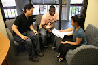 Alana Okamoto takes the time to review Jonathon McNair's personal budget while advisor Mike Chen looks on
