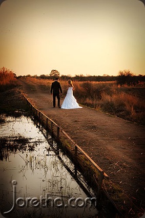 Bride and groom walking over bridge in setting sun - Joretha Taljaard Wedding Photography
