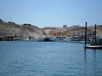The far side of the bay has concrete docks that are fixed and filled with trawlers.