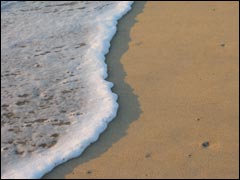 A small wave ebbing and flowing across a beach