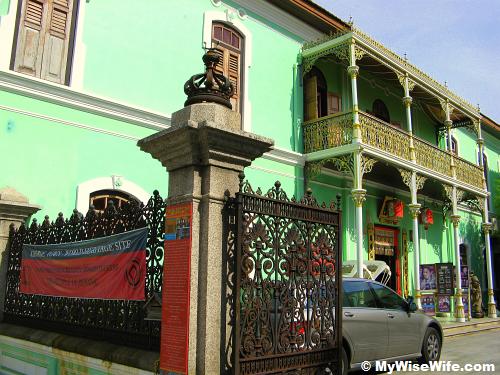 Iron gate and balcony with pale green facade Iron gate and balcony with pale green facade