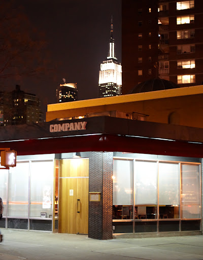 The exterior of Co. with the Empire State Building shining proudly in the background.