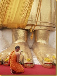 252-10492~Buddhist-Monk-Kneeling-in-Prayer-at-the-Feet-of-a-Statue-of-the-Standing-Buddha-Thailand-Posters