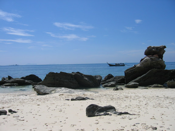 a beach with rocks and a boat in the water