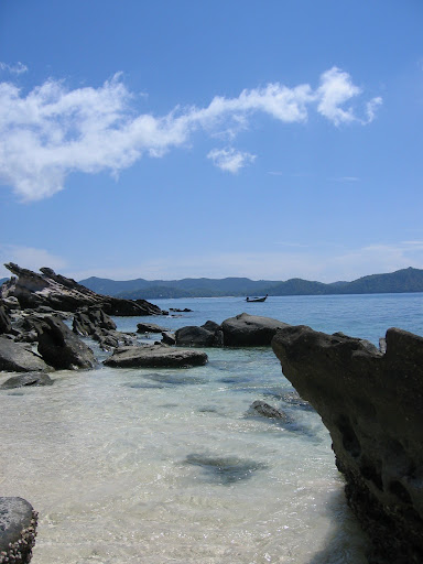a rocky beach with water and mountains in the background