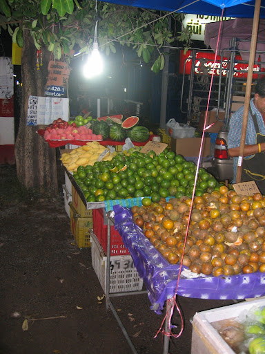 a fruit stand with a man standing behind it