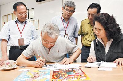 王泽现场在老夫子画上题字，为本报庆100周年纪念祝贺。