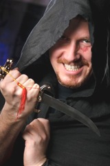 medieval looking menacng man with dagger wearing black cloak with hood medieval looking menacng man with dagger wearing black cloak with hood