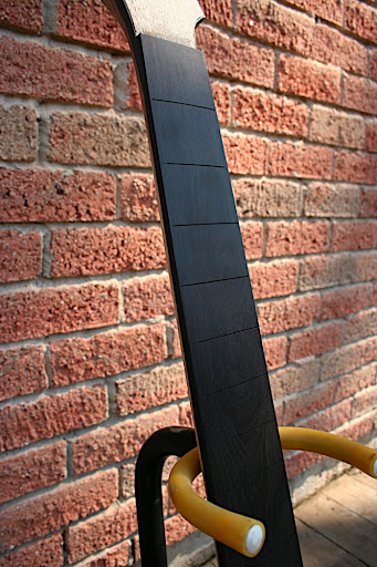 The ebony board has black binding on it, which ties it into the black binding around the rest of the guitar's top. The finished look will be super-clean.