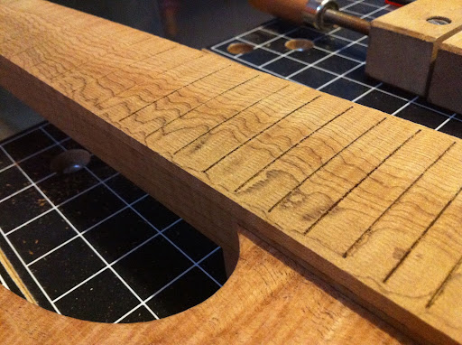 The fretboard needs some fine sanding to bring back the figure. Wavy grain = crazy figure. The 16" to 20" compound radius and the fret slots were cut on CNC. The slots end short of the edges to give a "pseudo-bound" look. The solid edges also likely make the fretboard a bit stiffer.