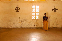 I live next door to Father William, an excellent old priest who has been in Malawi since the the seventies with the Catholic Order of the White Fathers. One Sunday Father William took me to one of the many remote villages where he leads Mass. The congregation sang wonderful, beautiful music that was punctuated by the sniffles and cries of too many babies. So many babies. Infants rarely leave their mother's backs, and then they are usually carried by a sibling. A mother does not disrupt daily life just because there is a little person on her back; I have seen mother-baby duos Church going, bicycle riding, even splitting fire wood together. This particular woman stayed around to read from a tattered old Bible for a few minutes after Mass ended. You can see her baby's legs sticking out underneath her elbows.