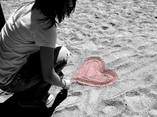 A Teen Girls to draw a Lovely Colorful Heart in Beach sand