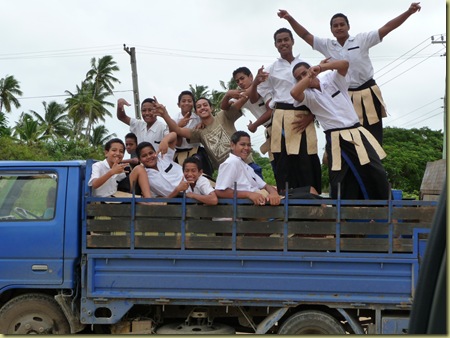Kids on the way home from a Tongan school wave as we take their picture.