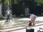 A little girl plays in a fountian with her father.