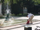 A little girl plays in a fountian with her father.