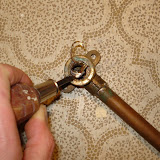 After gingerly weakening the metal in a few spots with the hacksaw, I pried it out with needlenose pliers and screwdriver