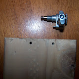 Here is a tuner and a couple of my test holes in a scrap piece of 2x4.  The hole is for that little piece that juts out on the side nearest the 2x4.  A good fit seems crucial, since it essentially does the job of a screw (that you'd find in many tuners).